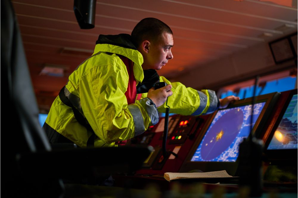 captain performing daily duties with VHF radio, binoculars on board of modern ship