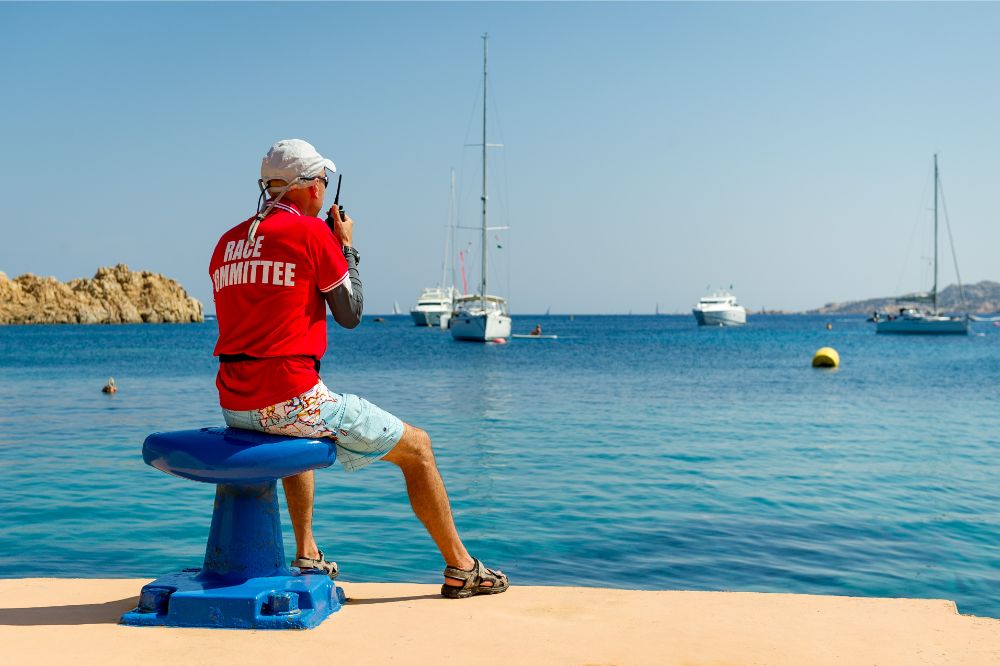 man holding a vhf radion watching at the yachts in beautiful bay